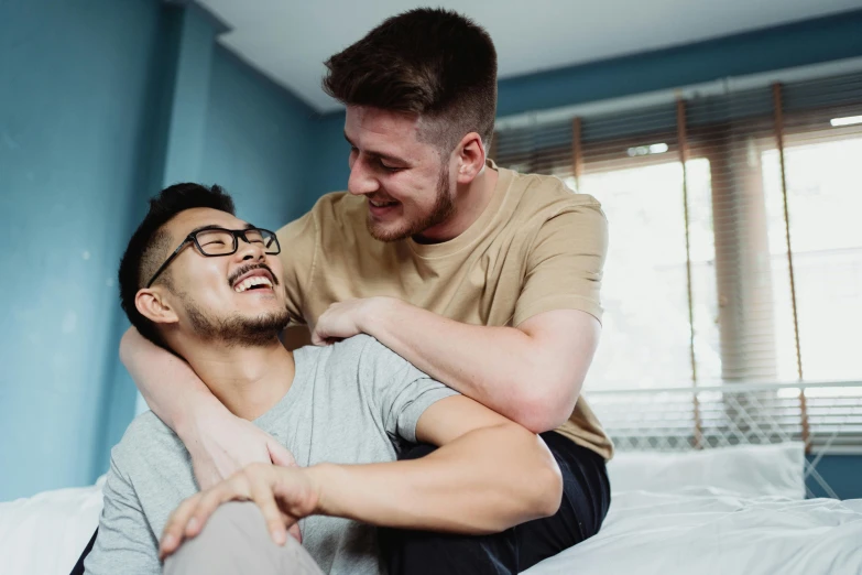 a male with glasses is being lifted on his knees by another male