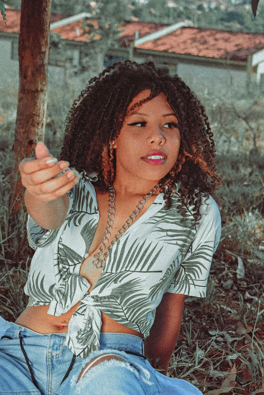 a young woman sitting on the grass next to a tree