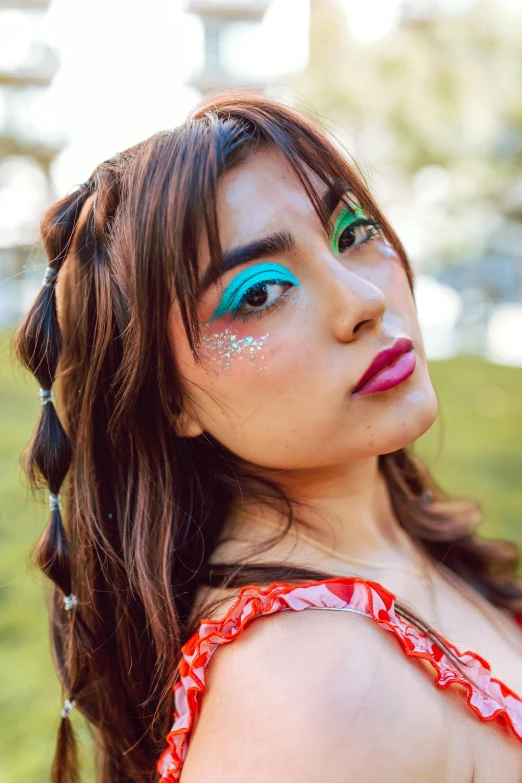 a woman wearing blue and red makeup with glitter on her eyes