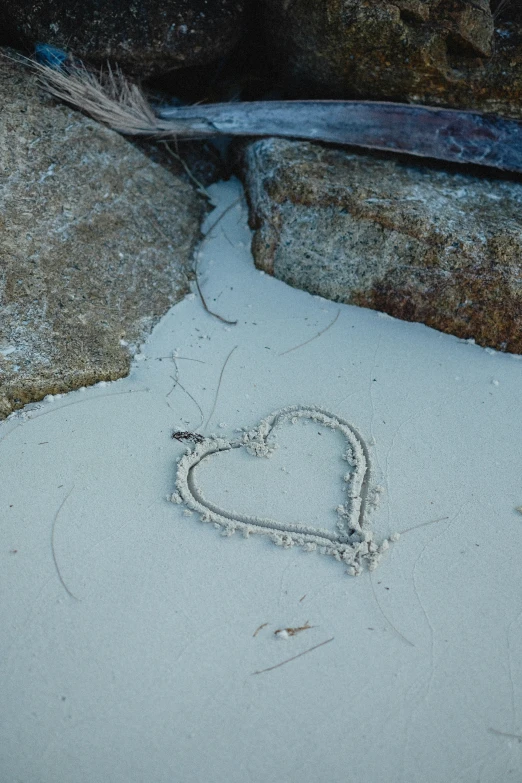 a broken heart is in the sand beside rocks