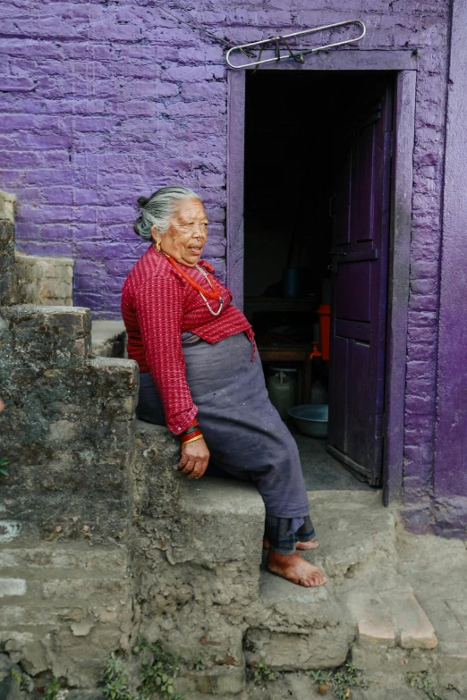 the old woman is sitting on the steps in her doorway