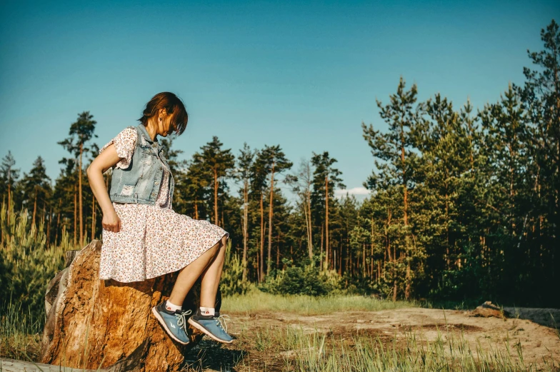 a young woman sitting on top of a log