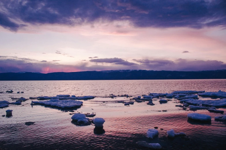 several pieces of ice floating in the water with mountains in the background