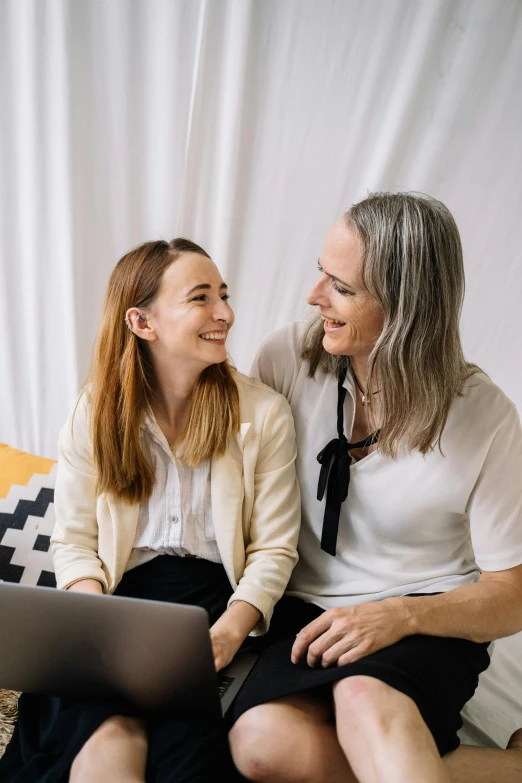 two smiling women sitting with their laptop computer