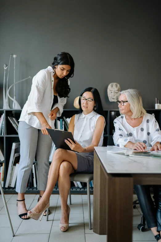 three woman sitting at a table and one has a computer