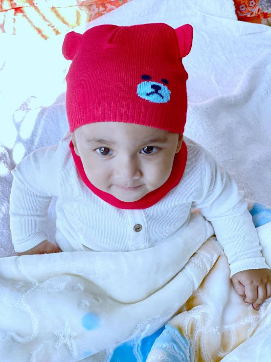 a baby wearing a red hat and smiling
