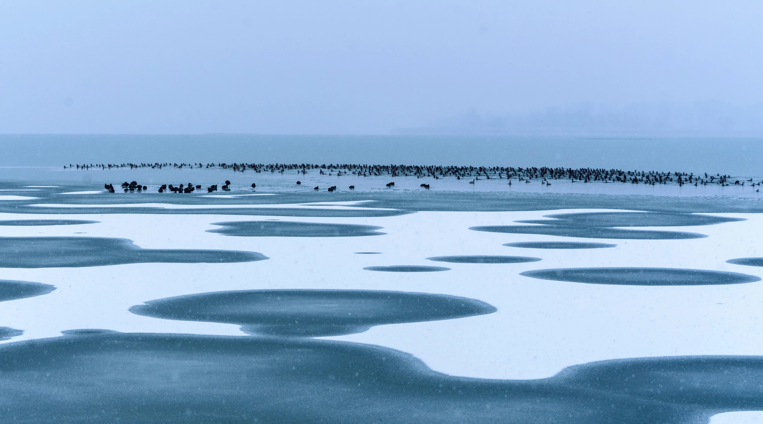 a group of people walking over a lake in the snow