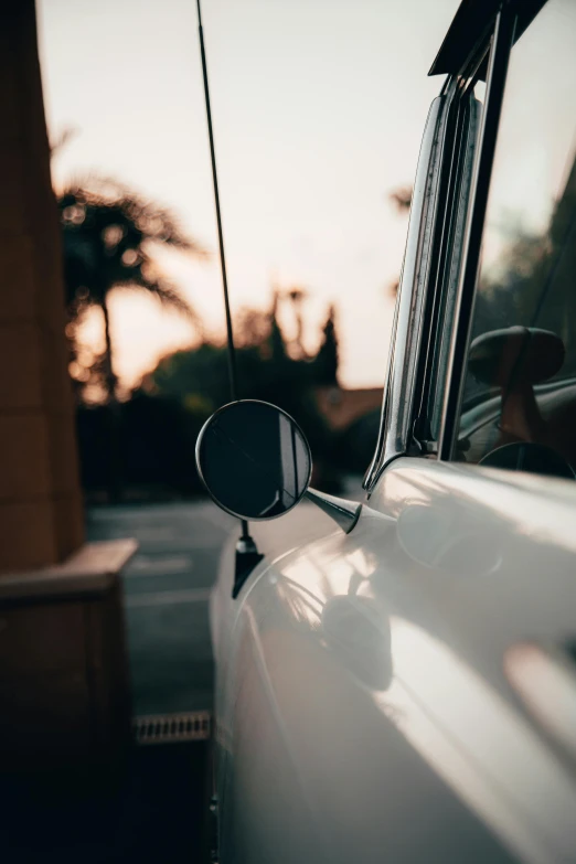 side view mirror of a white car with the sun shining on it
