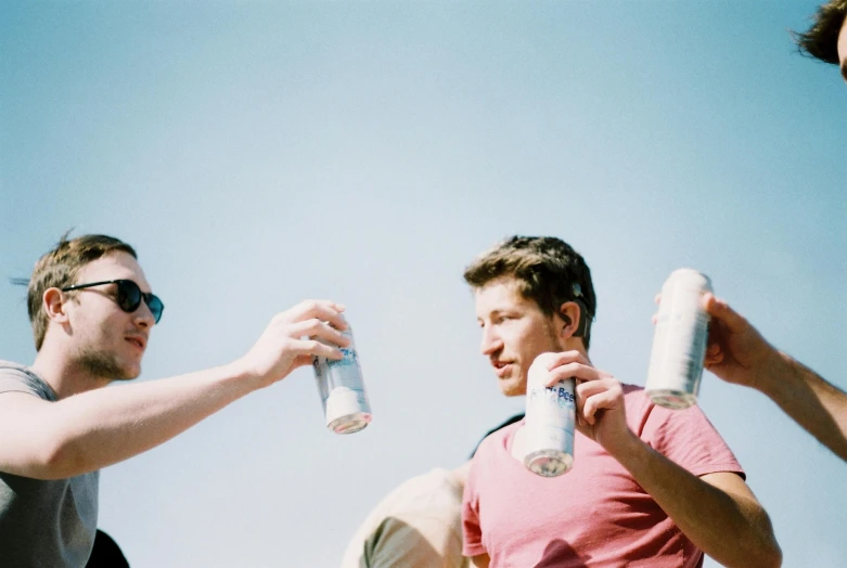 three men with a tennis racket and one drinking water