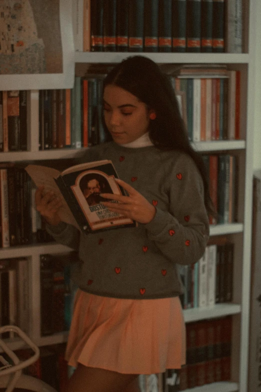 a woman holding a book next to a bookshelf filled with books