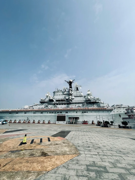 a large military ship at sea, surrounded by sand