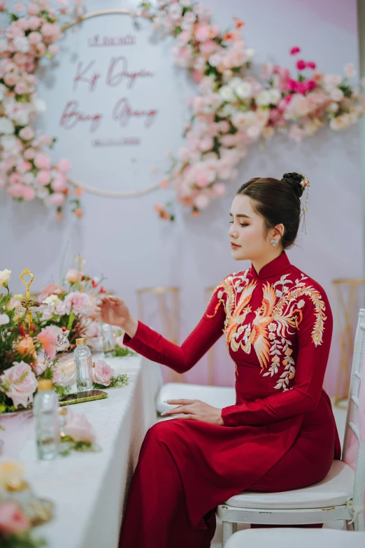 a young woman wearing a traditional chinese garb is at a table