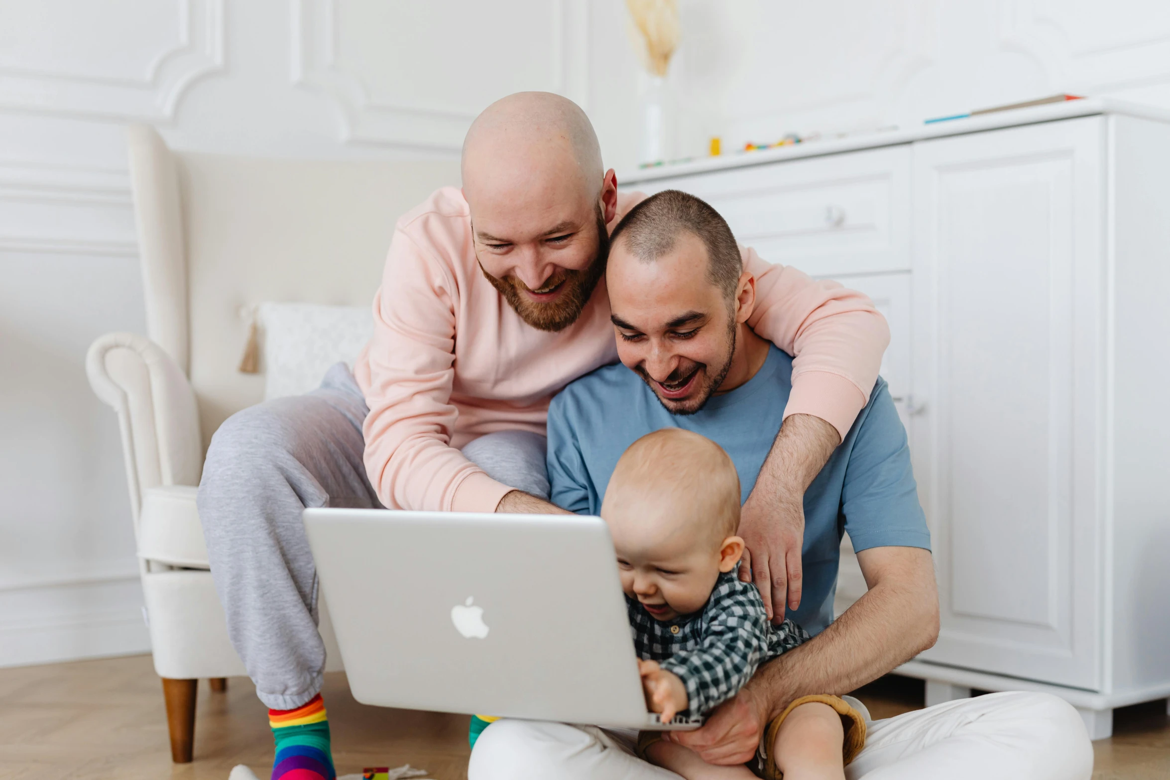 two men, a baby and an adult, playing with an apple computer