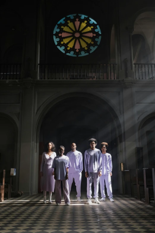 people standing in a large building with a colorful window above them