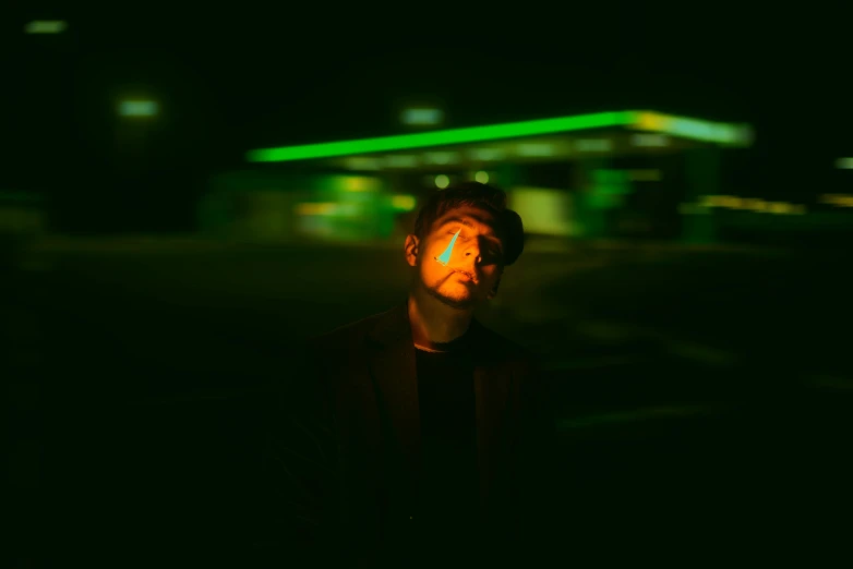 man looking up at green light at night