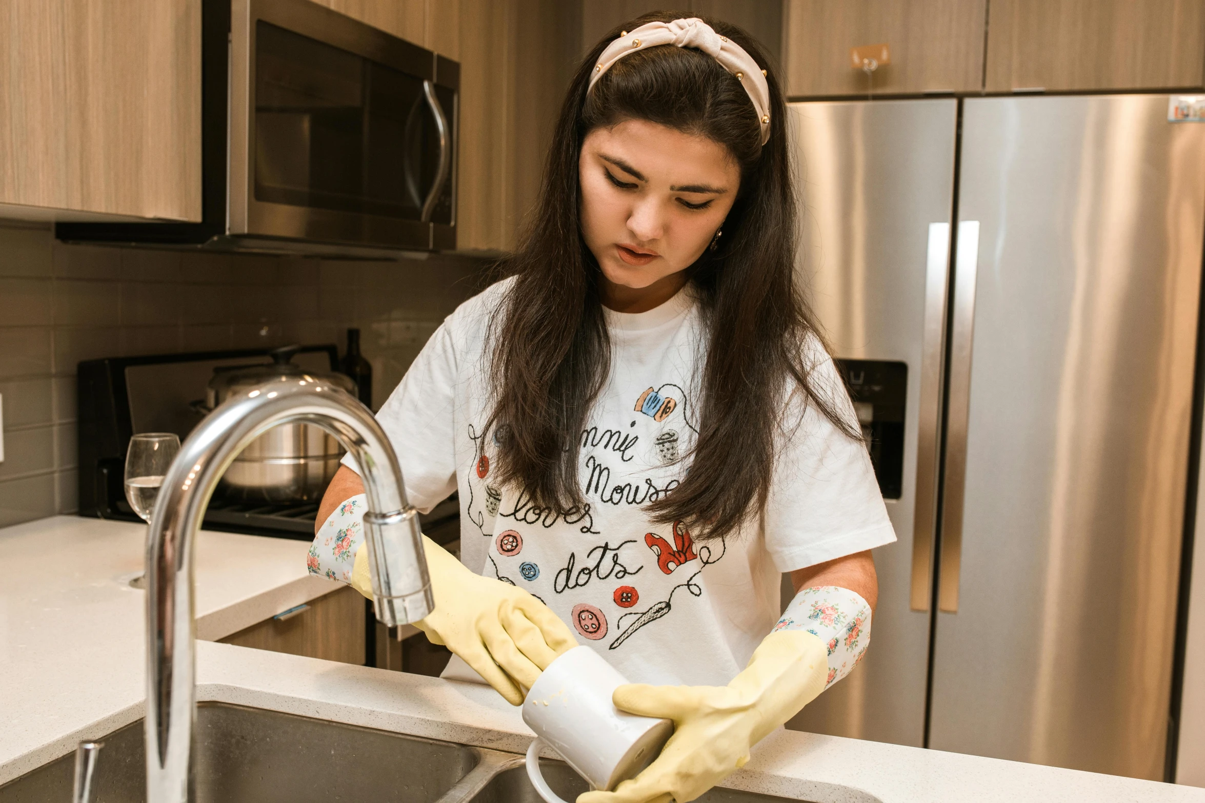 a woman wearing gloves is washing a sink