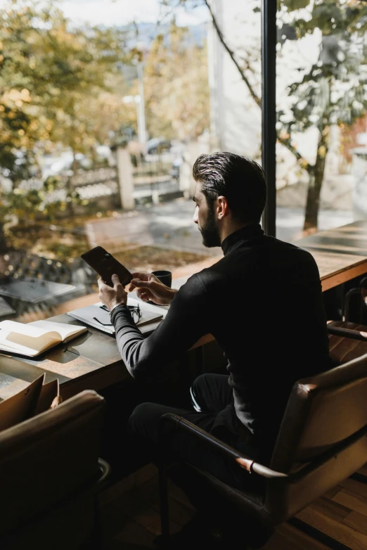 a man sitting at a table using a tablet computer