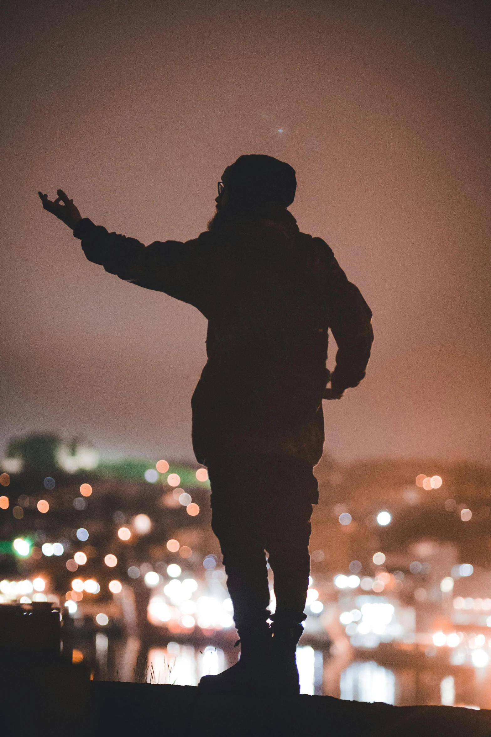 silhouette of person in city at night with arms extended