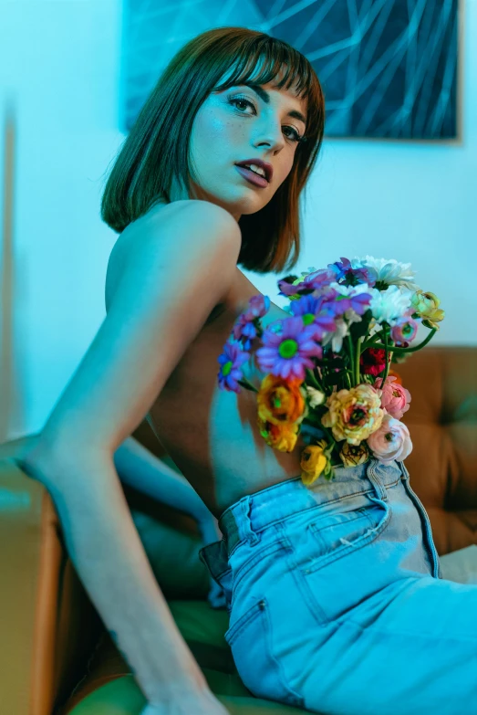 a woman with no panties and blue jeans with a bouquet of flowers on her stomach