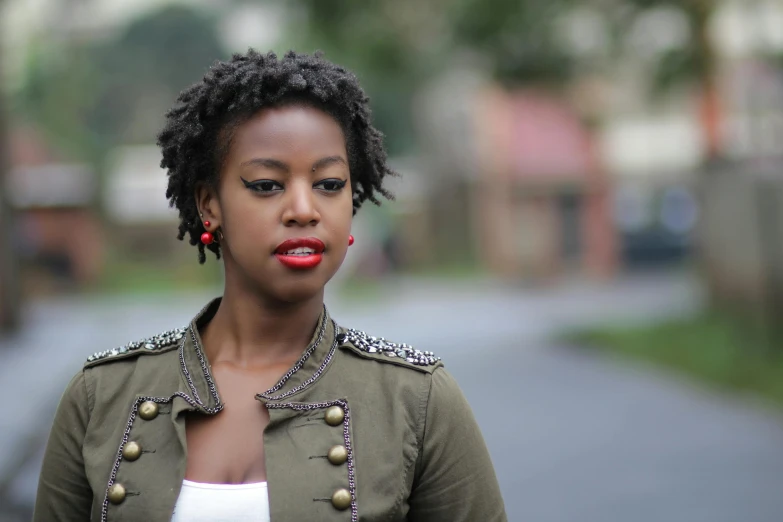 a girl with earrings and red lips posing on the side of a street