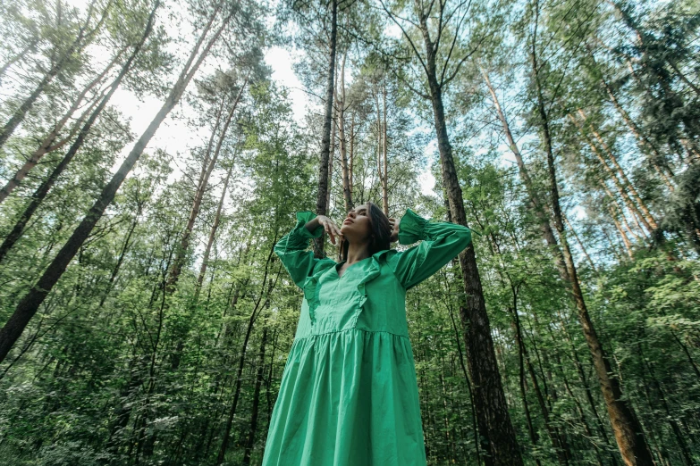 a woman wearing a green dress standing in the woods