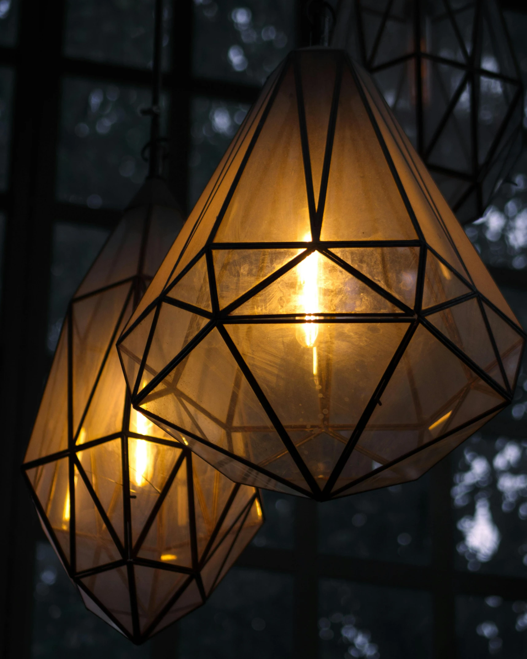 three hanging lights in a room by some trees