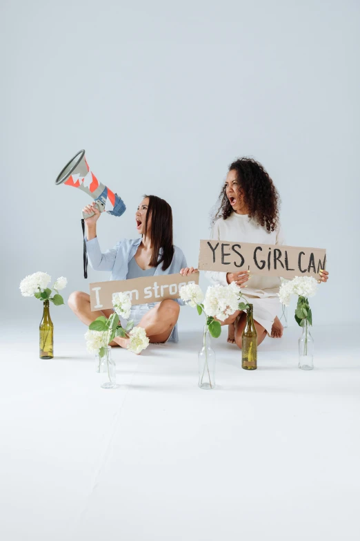 two beautiful young women holding signs while sitting on the floor