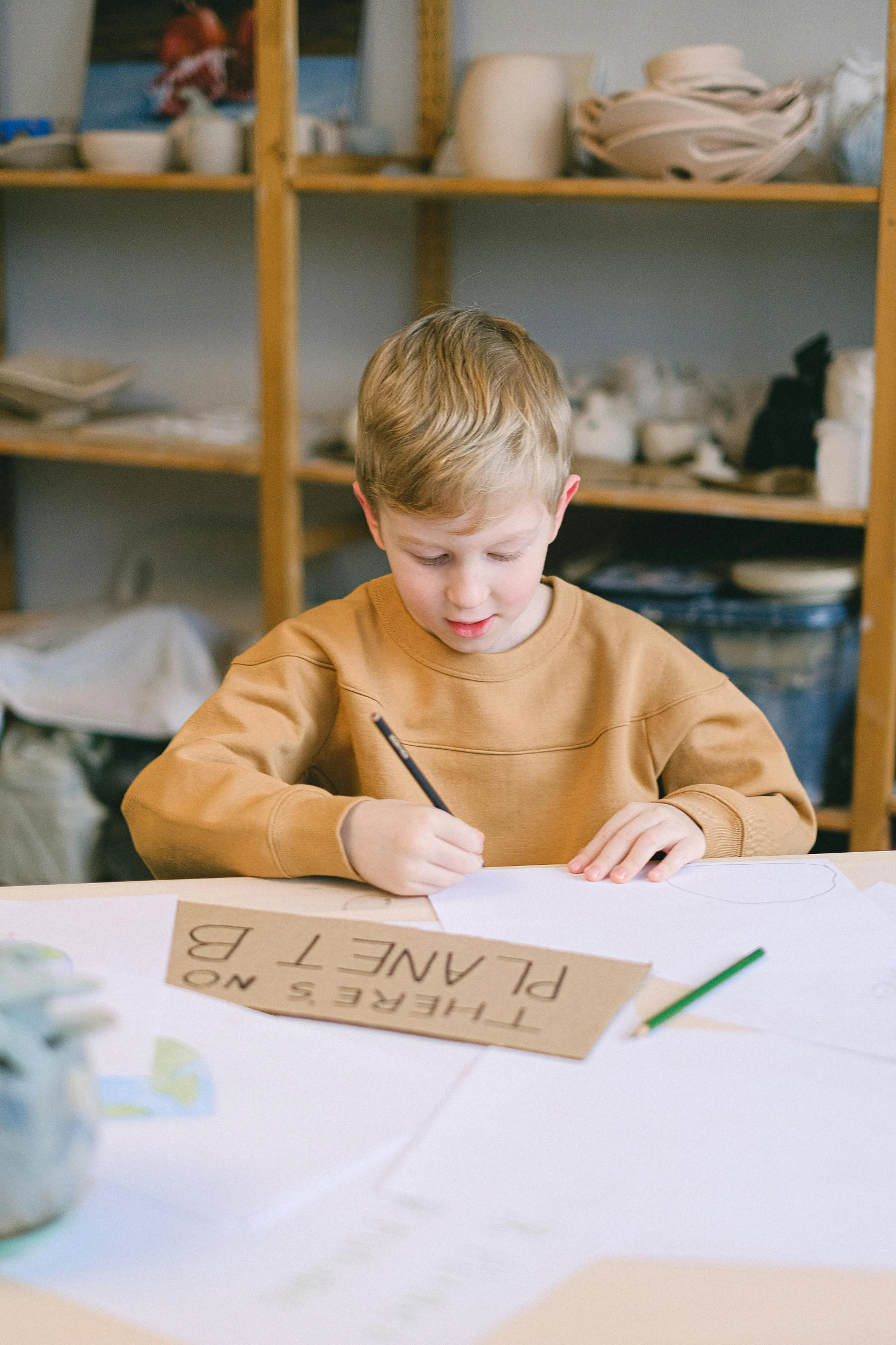 a little boy who is sitting at a table writing