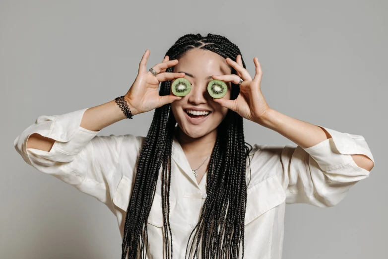 a woman has two cut - up avocados placed between her eyes