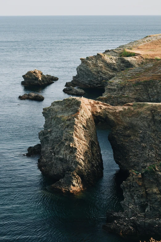 a rocky beach next to an ocean line on a clear day