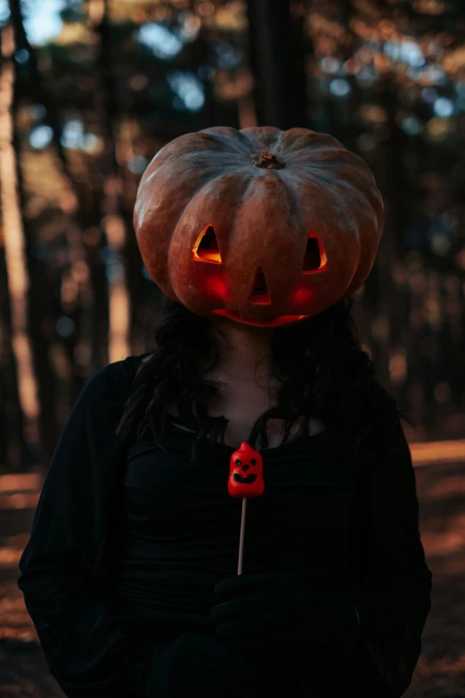 a woman wearing a lighted pumpkin hat in a forest