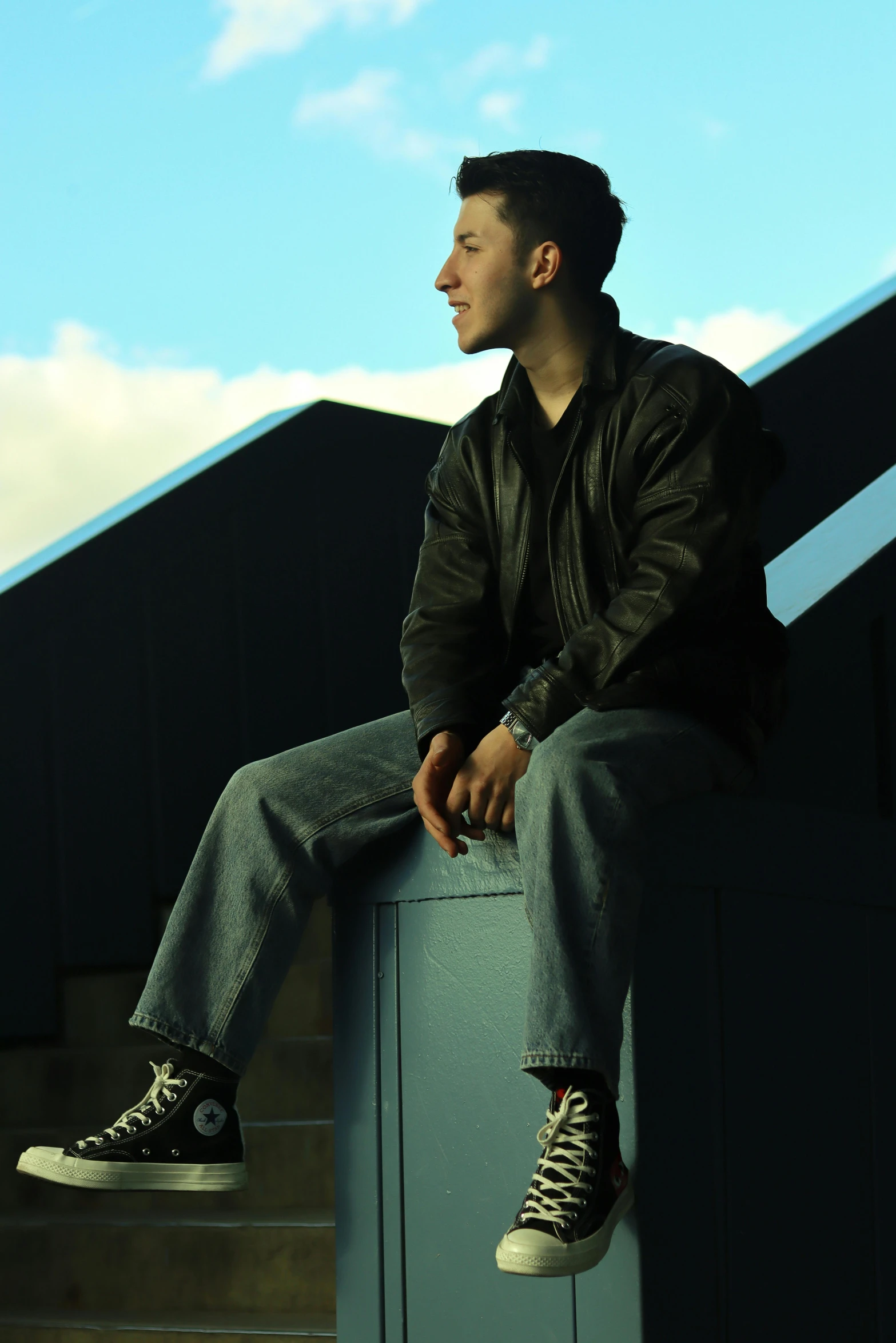 a man sitting on top of a metal hand rail