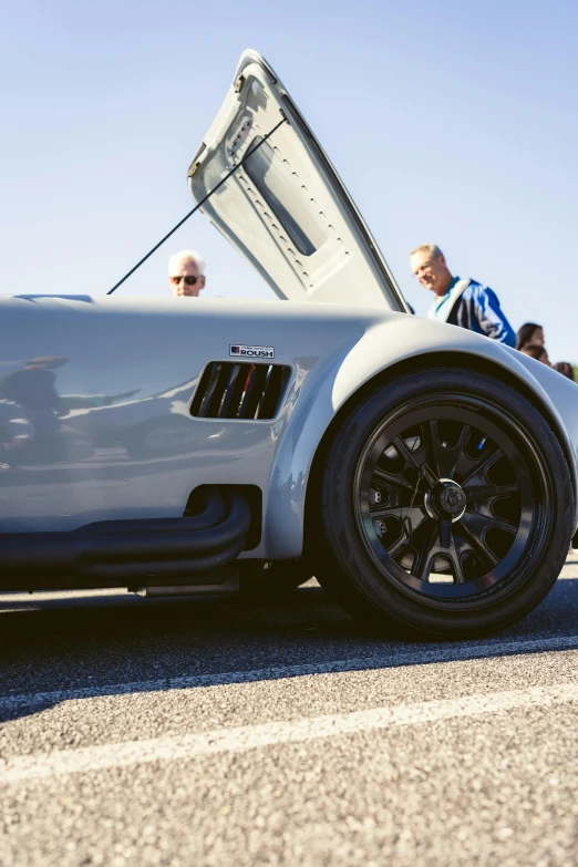 an old man sits in the open top of a sports car