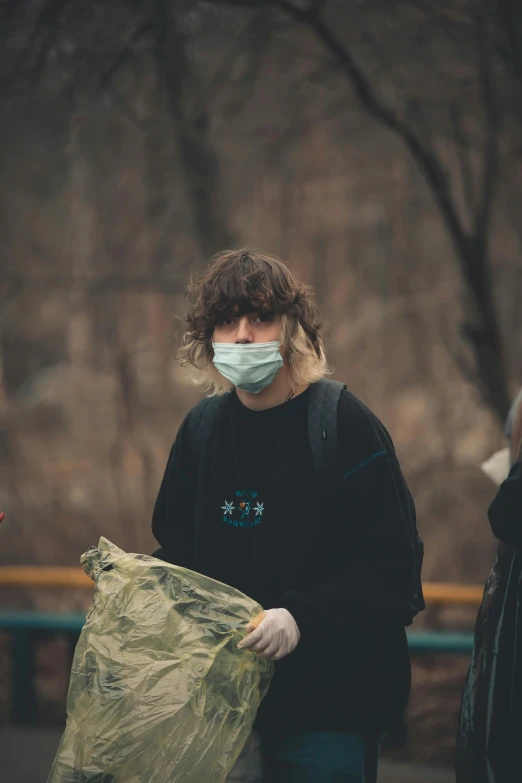 a person wearing a mask while holding garbage bags