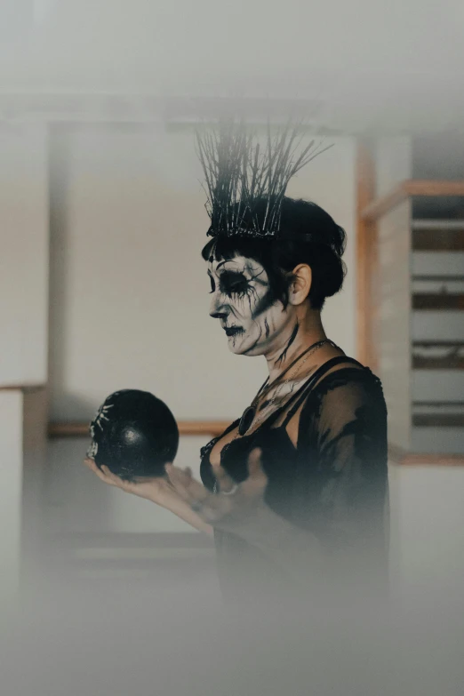 a person with makeup holding a bowling ball