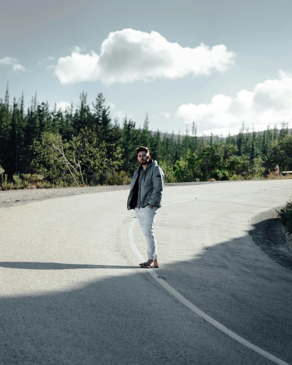 a man walking on the road with trees and trees in the background