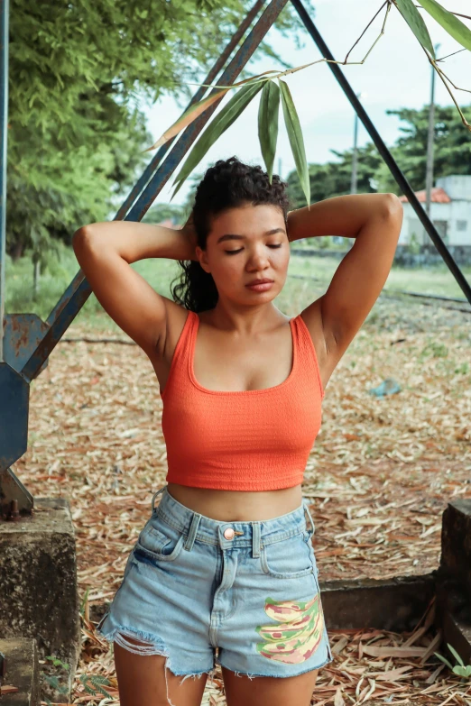 a woman wearing a pair of ripped shorts and an orange tank top