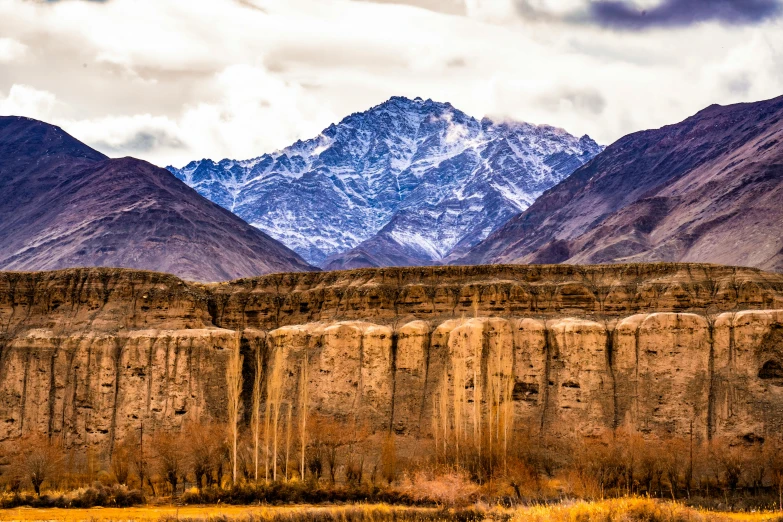 mountains are next to some rocky structures and grassy plains