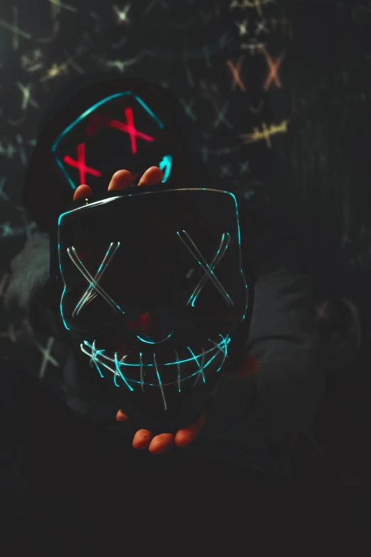 someone holding up a neon skull mask to the camera