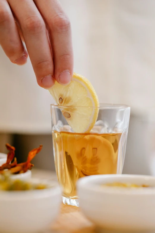 someone using a toothpick to pull the lemon from the cup