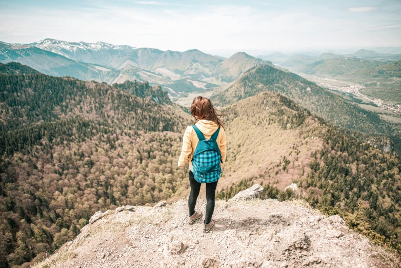 a girl wearing a backpack on top of a mountain