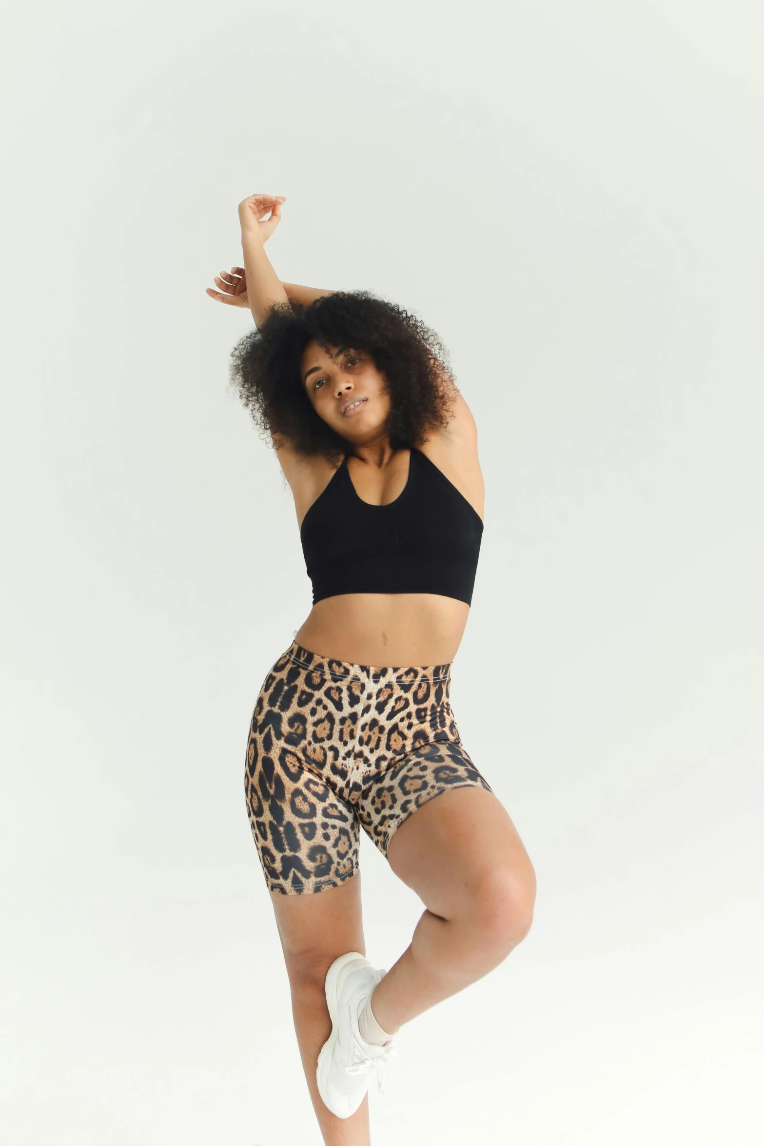 a woman posing on a white background wearing leopard print shorts