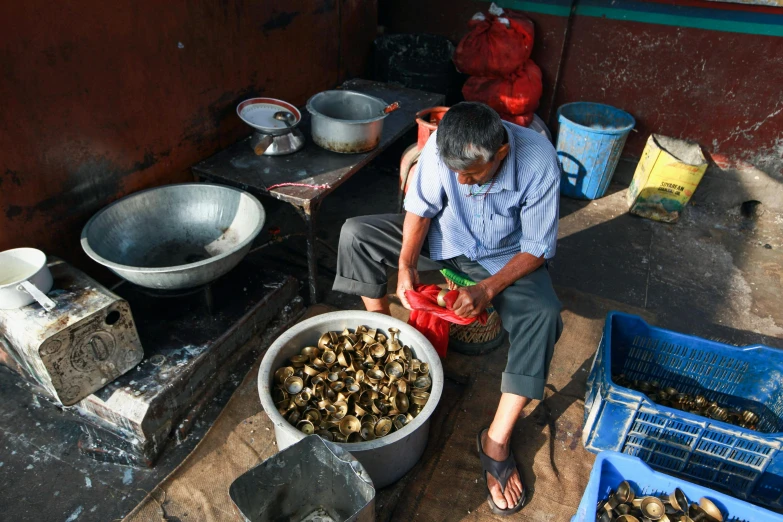 man sitting on cement steps with various containers and bowls around him