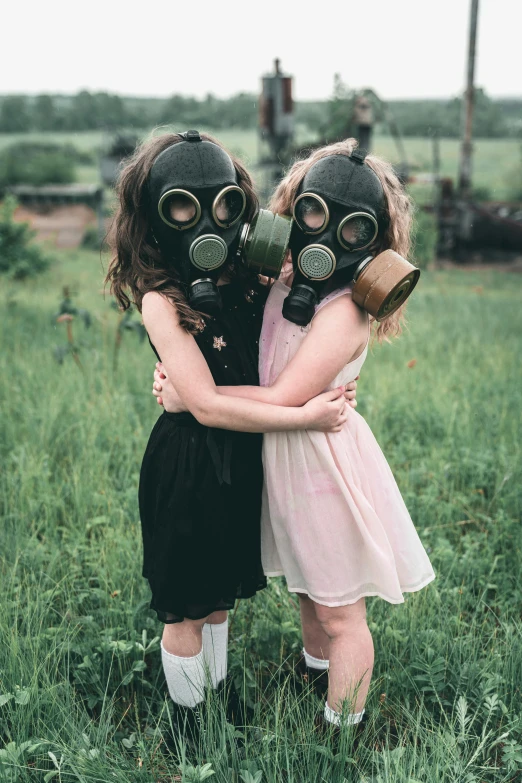 two little girls with gas masks are hugging