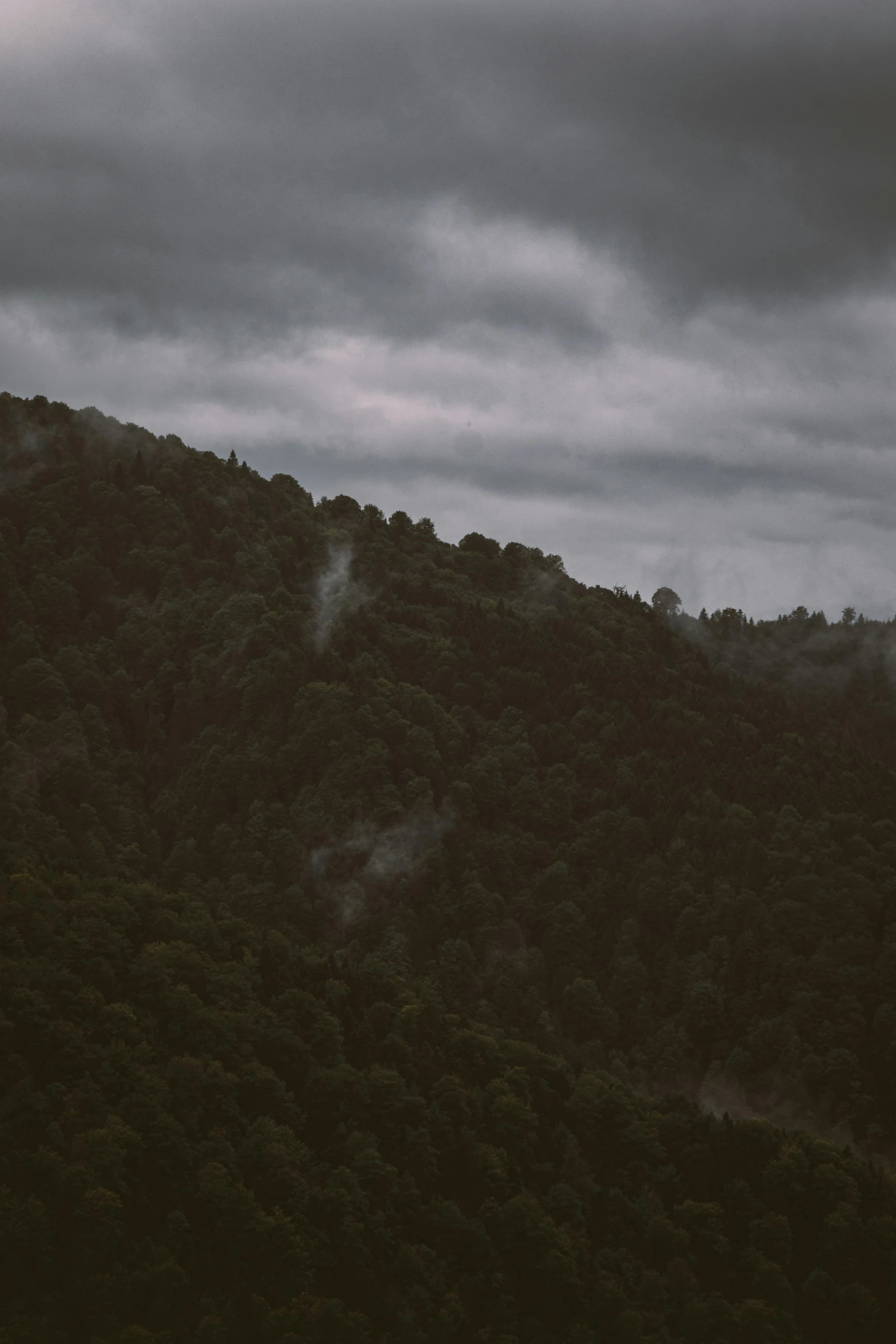 a dark sky is over some mountains covered in fog