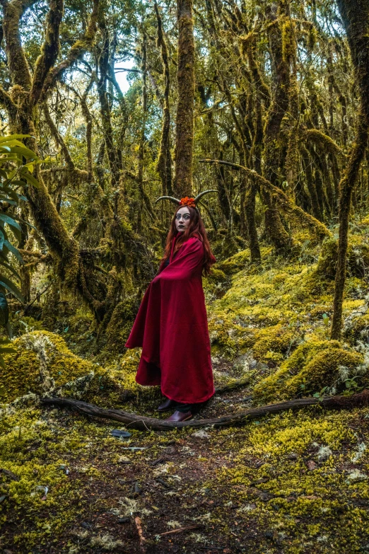 a woman in red is posing by some trees