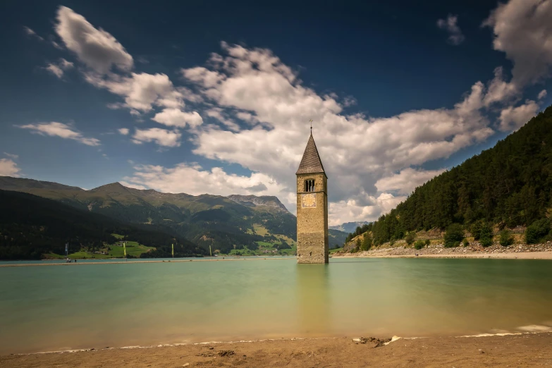 water under some clouds near a building that is built into the hillside side