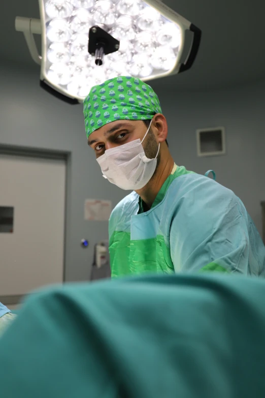 surgeon wearing green scrubs in his hospital surgical gown