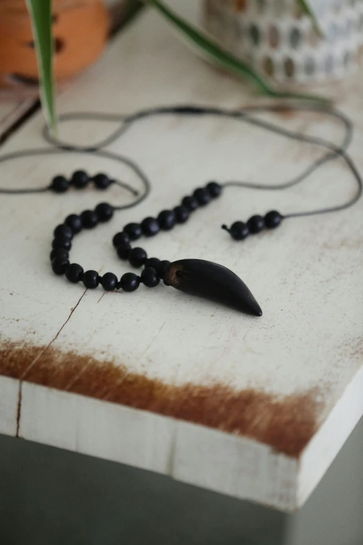 a necklace has a long black beaded chain with a single black pendant hanging from it