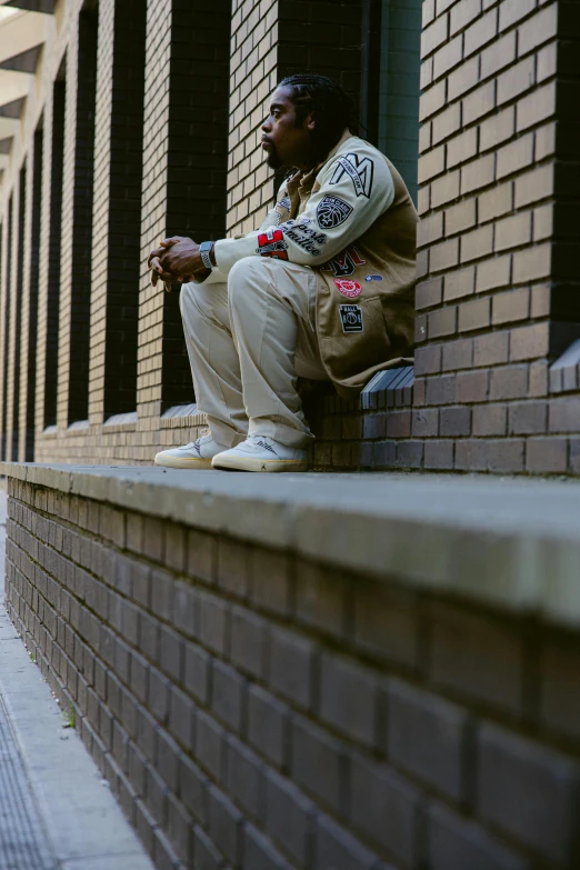 a young man sits on the step next to a wall